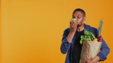 Afro-Amerikalı vejetaryen adam olgun, doğal yeşil bir elmadan bir ısırık alıyor ve stüdyoda taze toplanmış organik meyveler yiyor. Yerel tarım ve etik kaynaklı ürünlerin reklamını yapan kişi. Kamera B.