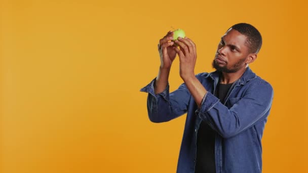 Αρσενικό Μοντέλο Που Εξετάζει Ένα Πράσινο Μήλο Για Είναι Καθαρό — Αρχείο Βίντεο