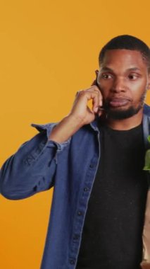 Dikey Videolu Genç Yetişkin, market alışverişi sırasında bir telefon görüşmesine cevap veriyor, bir kese dolusu çevre dostu ürün taşıyor ve akıllı telefondan konuşuyor. Yerel çiftçilik ilanları. Kamera.