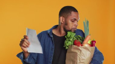 Sağlıklı beslenmek için ihtiyacı olan her şeyi almak için market alışveriş listesini kontrol eden vejetaryen kişi, yerel sıfır atık mağazasından aldığı önemli bir malzemeyi unutmuş. Kamera A.