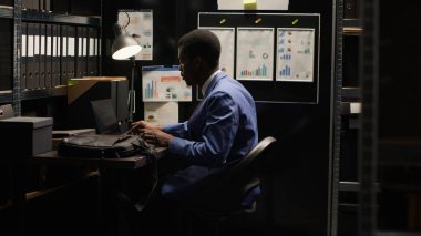 İş yerine varan, kriminal soruşturma deneyimi olan siyah bir adam mini bilgisayarını açıyor. Afrika kökenli Amerikalı araştırmacı çalışma odasında laptop çantasıyla oturup çalışmaya hazır..