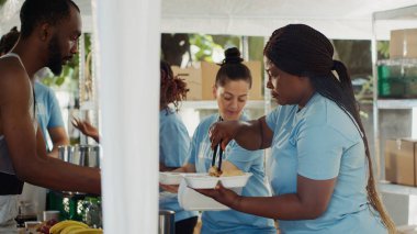 Yoksullara taze yiyecek sunan genç hayır işçileri, evsiz ve mültecilere destek ve yardım sağlıyorlar. Fakir ve aç bireyler açık hava gıda bankasında bedava yemek yiyor..