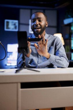 Stüdyodaki nüfuzlu kişi canlı yayını kaydetmek ve cep telefonunu incelemek için akıllı telefonu kullanıyordu. Çevrimiçi şov sunucusu, yeni başlatılan cep telefonunu izleyicilere sunuyor.
