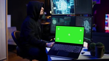 Siber suçluların saklanma yerlerinde kod ve kötü amaçlı yazılım senaryoları yazmak için kullandıkları izole ekran bilgisayarı. Kötü programcı tarafından gizli sığınakta kullanılan model defter, yakın çekim, kamera B