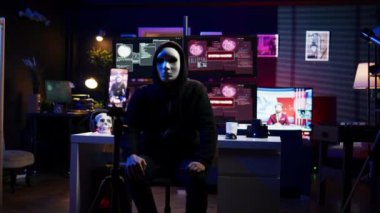 Hacker 'ın gizli yeraltı üssünde fidye videosu saklaması, ödeme talepleri karşılanmazsa çalıntı verileri halka açıklamakla tehdit etmesi, şantaj görüntülerini kaydetmek için telefon kullanması, kamera B