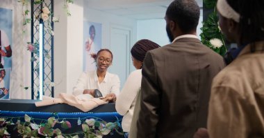 Dost canlısı bir çalışan, kadın giyim mağazasındaki diğer müşterilerle sırada beklerken, onunla hoş sohbetler eder. Moda mağazasından müşteriler tarafından satın alınan giysileri tarayan işçi.