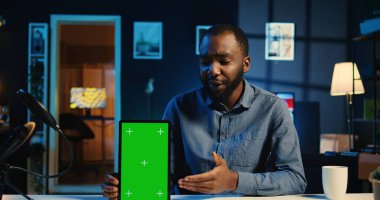 Teknoloji içeriği üreticisi yeşil ekran tabletini boks yaparken çekiyor ve satın almak için nedenler sunuyor. Nüfuz Edici, aboneleri sponsor partner modelleme aygıtı almaya teşvik eden video kaydı yapıyor