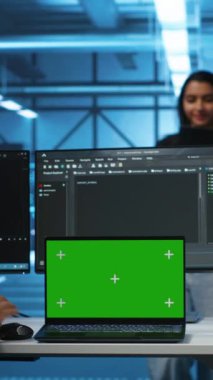Sunucu merkezindeki dikey video denetleyicisi yeşil ekran dizüstü bilgisayar kullanarak farklı geliştirici takımlarını yönetiyor. Veri merkezindeki hataları kroma ile onaran uzmanları koordine eden yönetici