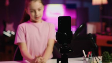 Gen Z çocuğu tarafından çevrimiçi kanal için çekim yapmak ve izleyicilerle konuşmak için kullanılan kayıt cihazlarının yakın çekim görüntüleri. Kid 'in bulanık arka planda kullandığı akıllı telefona odaklan genç izleyicilerle konuları tartış