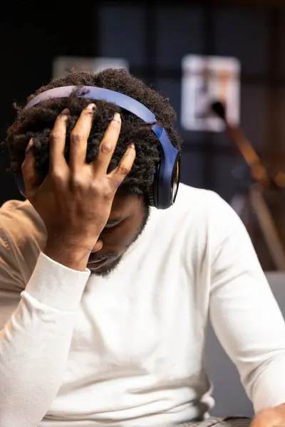 stock image Gamer wearing headphones face palming himself in frustration after getting game over message while playing videogame. Man feeling depressed while playing on gaming console after losing