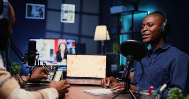Afrikalı Amerikalı nüfuzlu biri, erkeklerle podcast yapıyor, stüdyoda konuşuyor. İnternet şovu için canlı yayında konuk dinleyen neşeli adamın görüntüsünü yakınlaştır.