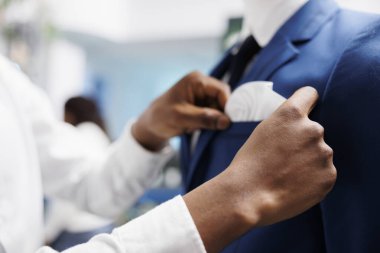 Afro-Amerikan erkek elleri elbise mağazasındaki mankenlere uygun resmi ceketleri kontrol ediyor. Alışveriş merkezi asistan kolları manken üzerinde giysi ayarlama, yeni giysi koleksiyonu gösteriliyor