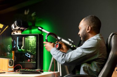 Afrika kökenli Amerikalı bir adam evde video oyunu oynarken kulaklık takarak kendini daha iyi bir duruma sokuyor. Çevrimiçi çok oyunculu esport turnuvasına katılan oyuncu, düşmanları yenmek için savaşıyor