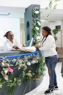 Afro-amerikan müşteri alışveriş merkezindeki kasada yeni kıyafet satın alıyor. Kadın müşteri giyim mağazasının kasasında kasiyer kıyafetlerini bekliyor.