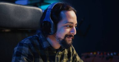 Evde müzik dinlerken kahve içip e-posta yazan mutlu bir adam. Gülümseyen uzaktan kumandalı işçi internet üzerinden b2b ağ kuruyor, kulaklık takıyor, sıcak içeceğin keyfini çıkarıyor, kamera B