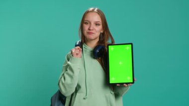 Stüdyo arka planında izole edilmiş, krom anahtar ekranlı tablet sunan kadın portresi. Genç kız boş fotokopi alanı ile promosyon yaratıyor dijital cihaz, kamera A