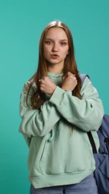 Dikey video kasetteki kadın X harfini kollarını kavuşturmuş, savaşçı duruşu sergiliyor, sertliğini gösteriyor. Reddedilme sinyali vermek için negatif vücut dili kullanan sert genç kişi, stüdyo geçmişi