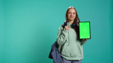 Stüdyo arka planında izole edilmiş, krom anahtar ekranlı tablet sunan kadın portresi. Boş fotokopi alanı ile promosyon yaratan genç kız dijital aygıt, kamera B