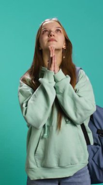 Dikey video Umutsuz genç kız kurtuluş için tanrıya dua ediyor. İbadet eden dindar genç, el hareketi yapıyor, mucize istiyor, günah çıkarıyor, stüdyo arka planında izole edilmiş, kamera B