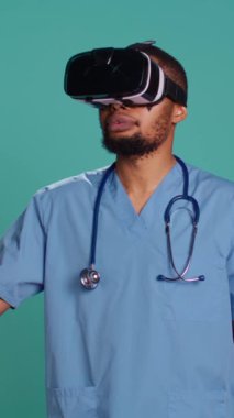 Sanal gerçeklik kulaklığı takan dikey video hemşire hastayı uzaktan ameliyat ediyor. İleri teknoloji modern tıbbi video aygıtı kullanan bir sağlık uzmanı. Mavi stüdyo arka planında izole edilmiş. Kamera.