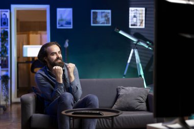 TV 'de yayınlanan canlı yayını izleyen mutlu adam favori takımı destekliyor. Evdeki koltukta oturan neşeli destekçi futbol yarışmasının tadını çıkarıyor, galibiyeti kutluyor.