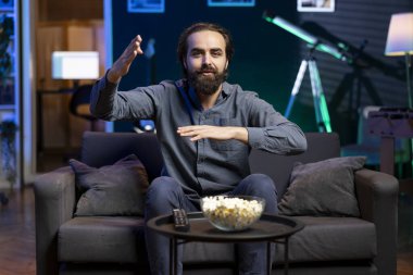 Canlı yayında spor maçı izleyen gülümseyen destekçi, teşvik edici bir takım. Neşeli adam futbol müsabakasına bakıyor, kazanması için oyuncuya tezahürat yapıyor.