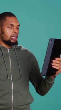 Dikey Videocu, video konferans sırasında arkadaşlarıyla eğlenceli bir konuşma yapıyor. Tablet kullanarak, stüdyo arka planı kullanarak. Taşınabilir internet video çağrısı sırasında arkadaşlarla etkileşim