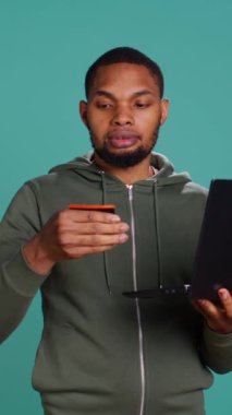 Dikey video Mutlu Adam dizüstü bilgisayarla siteye ödeme metodu ekliyor. Terfilerden ve stüdyo geçmişinden yararlanmaya bayılıyor. İnternet alışverişi yapmaktan, kredi kartı verilerini yazmaktan heyecan duyan biri.