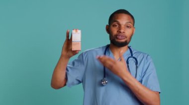 Yüksek korumalı güneş kremi ürünleri kullanmanın öneminden bahseden doktor portresi, stüdyo arkaplanı. Afrikalı Amerikalı sağlık uzmanı insanlara ultraviyole krem ve kamera A kullanmalarını söylüyor.