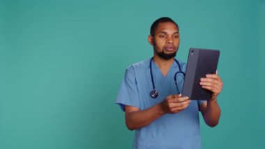 Video konferansında gülümseyen doktor tablet kullanıyor, semptomları duyuyor ve tanı koymaya çalışıyor. Çevrimiçi teletıp çağrısında hasta sağlığıyla ilgili sorunları dinleyen Mutlu Sağlık Uzmanı, Kamera B