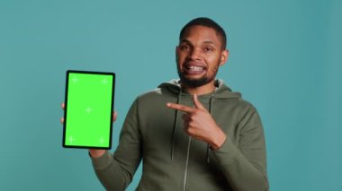 Neşeli Afro-Amerikalı adam, izole edilmiş bir bilgisayar tutuyor ve tavsiye veriyor. Renkli anahtar cihazını gösteren iyimser kişi pozitif geri bildirim, stüdyo arka planı, kamera A