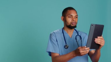 Video konferansında gülümseyen doktor tablet kullanıyor, semptomları duyuyor ve tanı koymaya çalışıyor. Çevrimiçi teletıp aramasında hastanın sağlık sorunlarını dinleyen Mutlu Sağlık Uzmanı, Kamera A