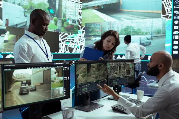 stock image Diverse team of supervisors overseeing their staff activity on gps locating, following delivery truck drivers around in traffic via satellite map. Operators guiding couriers on routes.