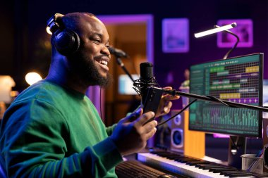 Yeni şarkısının akustik versiyonunu söyleyen yetenekli bir besteci, şarkıyı kaydetmek ve DAW yazılım arayüzünü düzenlemek için mikrofon kullanıyor. Şarkı sözü yazarı ev stüdyosunda müzik üzerine çalışır..