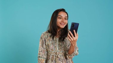 Telekonferans toplantısında gülümseyen bir kadın akıllı telefon ve stüdyo geçmişi kullanarak arkadaşça konuşmalar yapıyor. Hintli insan arkadaşlarıyla çevrimiçi video görüşmesi yaparken eğleniyor, kamera A