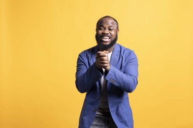 Aşırı neşeli Afro-Amerikalı bir adamın portresi. Çok gülüyor, komik şakalar yapıyor, stüdyo geçmişi ile eğleniyor. Mutlu BIPOC insanı kıkırdıyor ve kıkırdıyor, komedyenden zevk alıyor, eğleniyor