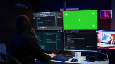 Dangerous man hacking using green screen PC, stealing credit card numbers and infiltrating banking systems. Hacker running code in apartment on mockup computer display, camera B clipart