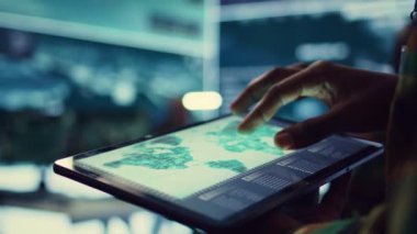 Donanma operasyon uzmanı tabletinde GPS sistemi olan bir dünya haritasını inceleyerek düşman gemilerinin izini bulmaya çalışıyor. General görevler için hükümet uydu verilerini kullanıyor. Kapatın. Kamera B.