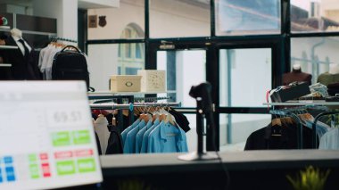 Yeni tasarımcı giyim markasıyla dolu terzi butiği, modaya uygun ürünlerle dolu askılar ve havalı aksesuarlar veya ayakkabılar. Havalı dış giyim ve küçük işletmeleri olan boş giyim mağazası. Kamera A.