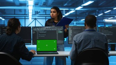 Bilgisayarlı bilgisayar destekçileri önünde bilgisayar kodlayan ve yöneticilerle konuşan, ekipmanları güncelleyen izole edilmiş ekran. Chroma anahtar defteri kullanarak sunucu kümelerini denetleyen bilgisayar masası mühendisleri