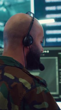 Yeni saha görevi için gerçek zamanlı veri iletmek için keşif sistemi üzerinde çalışan dikey video erkek bilişim uzmanı askeri komuta merkezinde çalışıyor. Telekomünikasyon operatörü hava sağlıyor