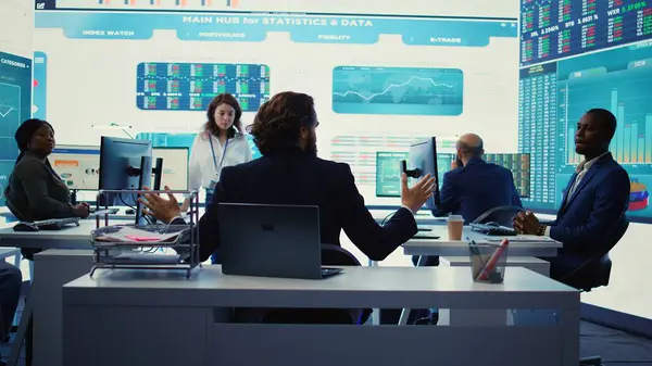 stock image Chairman of the advisory board transmits potential company expansion plans, supervisor and the staff look into data visualizations on a big screen. Teamwork to boost affordable earnings. Camera B.