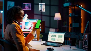 Öğrenci, ekonomi kursu araştırması için nakit planı yazılımını incelerken telefon düzeni üzerinde yeşil ekran kullanıyor. Masrafları ve kazançları öğrenen bir kız boş bir telif alanına bakar. Kamera B.