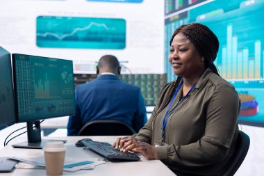 İcra subayı ofisteki büyük ekranda gösterilen verileri inceler, bilgi ekranları, finans analizleri ve organizasyonel gelişmeleri inceler. Haberleşme Sistemleri Kontrol Odası.