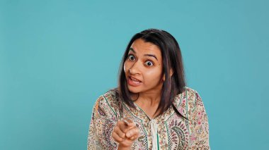 Upset indian person fighting with friend, doing scolding gesturing, isolated over studio backdrop. Annoyed woman arguing with opponent during discussion, doing admonishing hand gestures, camera B clipart