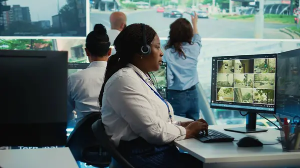 Stock image African american employee monitoring traffic activity in the city by using CCTV system to ensure public safety. Woman watches real time surveillance footage in government observation room. Camera B.