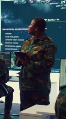 Dikey video kadın ordu subayı büyük ekrandaki taktik verileri girmek ve işlemek için radar gözetleme görüntülerini denetliyor. Kadınlar savaş alanı haritaları yaratmak için küresel keşifleri kullanırlar. Kamera.