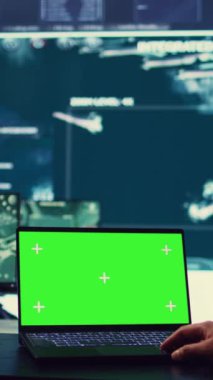 Dikey video ordu subayı kontrol odasındaki bir dizüstü bilgisayarda izole edilmiş yeşil ekran görüntüsü üzerinde çalışıyor. Askeri güç üssü personeli federal operasyonlar için uydu dünya haritasını izliyor. Üniformalı Komutan