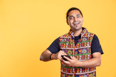 Akıllı telefon kullanan, sosyal medyada büyüleyici bir fotoğraf gördükten sonra olumlu duygular besleyen harika bir insan portresi. Telefon tutan, eğlenen, stüdyo geçmişi olan şaşkın bir adam.