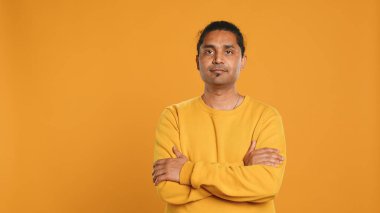 Neşeli, neşeli, neşeli, neşeli, mutlu, stüdyo arka planında soyutlanmış Hintli bir adam portresi. Neşeli insan sırıtıyor, kollarını kavuşturuyor, tatmin oluyor.